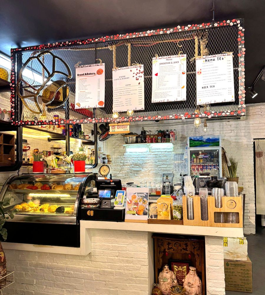Quầy bánh với tủ kính bày bánh mì và bốn bảng giá treo bên trên