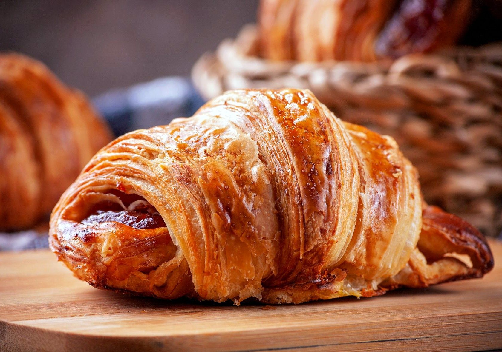 Chiếc croissant bơ vàng ruộm còn rõ từng lớp vỏ, đặt trên thớt gỗ