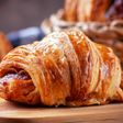 Chiếc croissant bơ vàng ruộm còn rõ từng lớp vỏ, đặt trên thớt gỗ