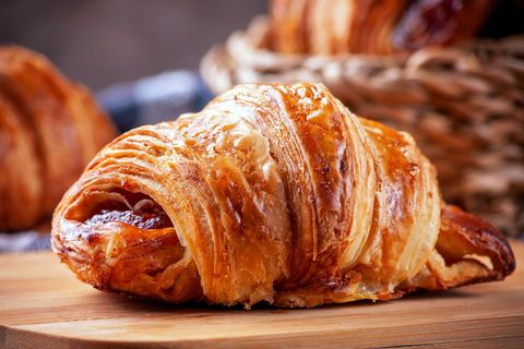 Chiếc croissant bơ vàng ruộm còn rõ từng lớp vỏ, đặt trên thớt gỗ